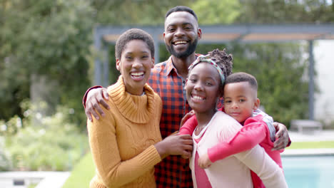 Portrait-of-happy-african-american-parents,-son-and-daughter-embracing-and-smiling-in-sunny-garden