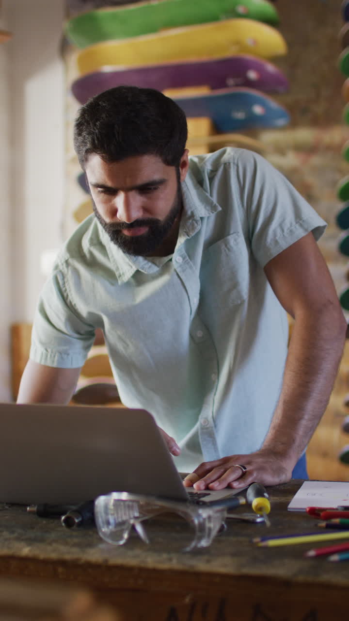 video vertical de un skateboarder caucásico usando una computadora portátil