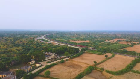 tomada aérea de un tren de carga que se mueve a través del valle de bosque semiárido del río chambal en la india