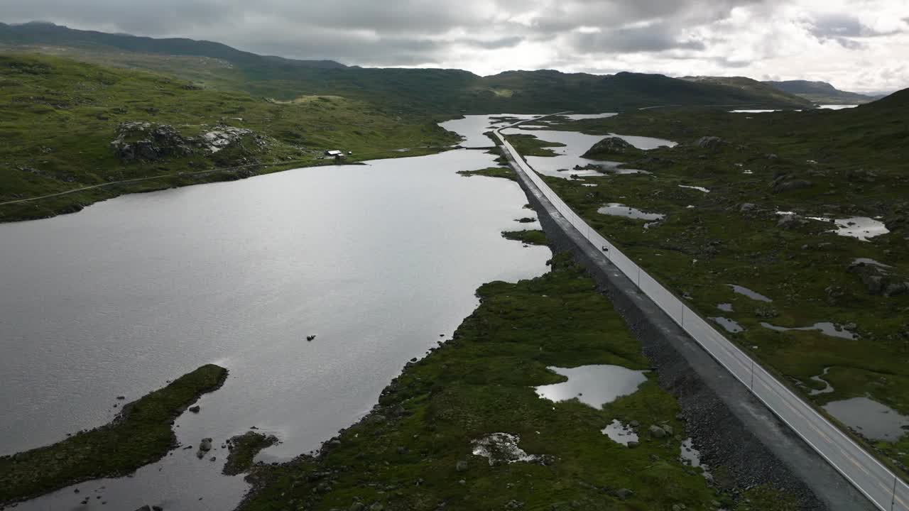 Norwegian road, drone pan right to left, sun and clouds, summer day