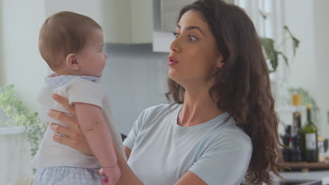 madre amorosa jugando con el hijo bebé en casa en el mostrador de la cocina