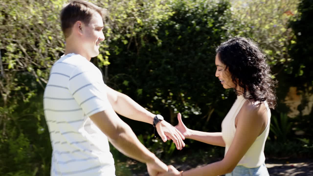Young multiracial couple walking and talking in garden, enjoying outdoor time together, copy space