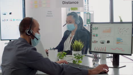 business team with headset talking into microphone while checking financial statistics