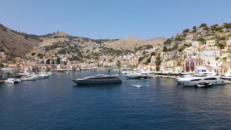 Drohnenaufnahme-Einer-Großen-Luxusyacht,-Die-Den-Hafen-Von-Symi,-Griechenland,-Verlässt