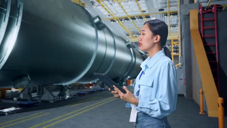 side view of asian business woman using tablet an looking around in pipe manufacturing factory