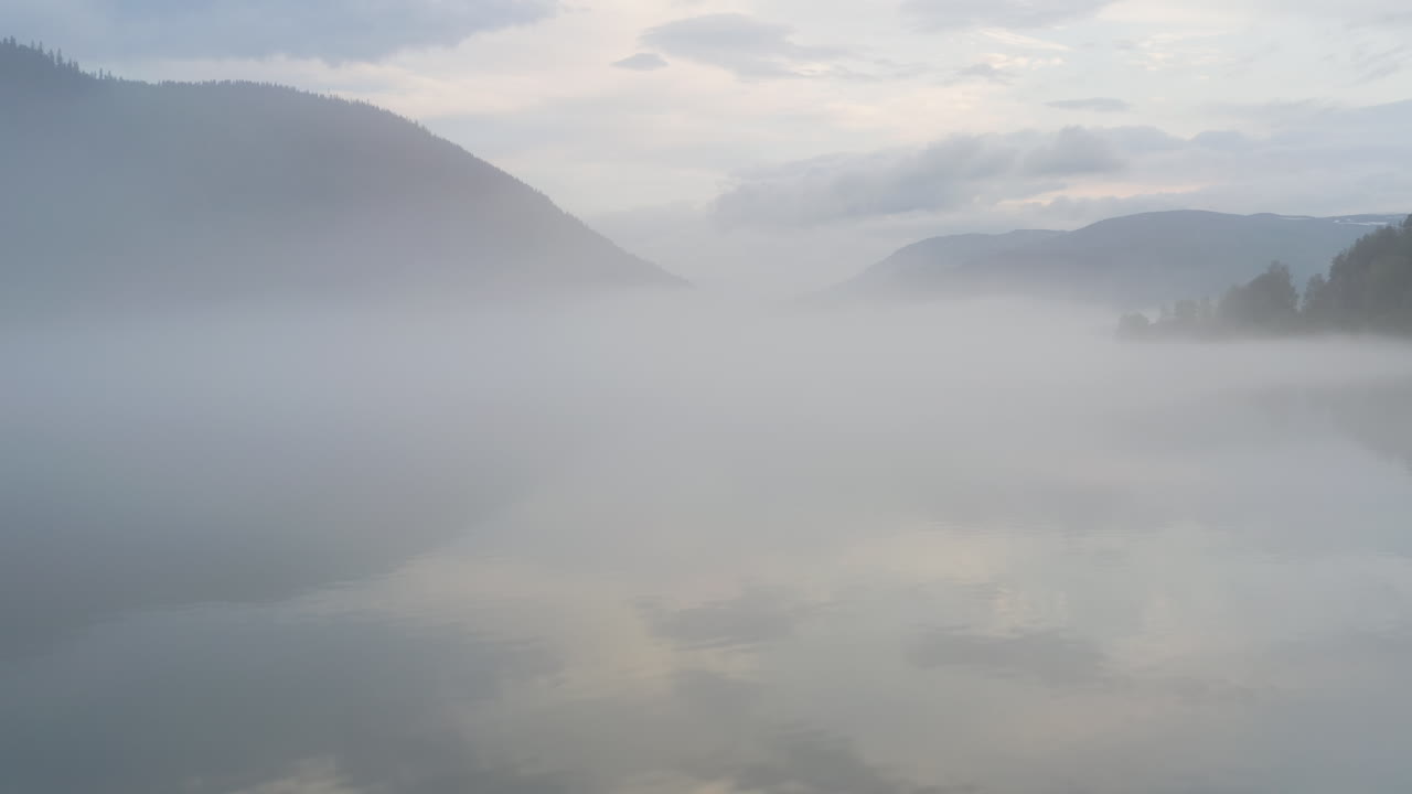 Flight over a foggy river. The mist is hanging low over the landscape creating a dark mystical mood over the whole scene.
