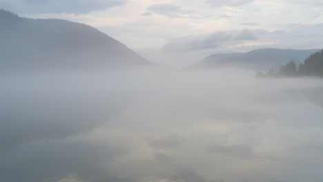 flight over a foggy river. the mist is hanging low over the landscape creating a dark mystical mood over the whole scene.
