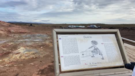 Caucasian-female-reading-the-poster-of-Icelandic-legend-at-Gunnuhver-volcanic-area