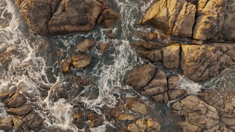 ocean waves splashing on rocks of a beach in costa rica - aerial top down