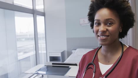 Portrait-of-happy-african-american-female-doctor-in-hospital-room-with-copy-space,-slow-motion