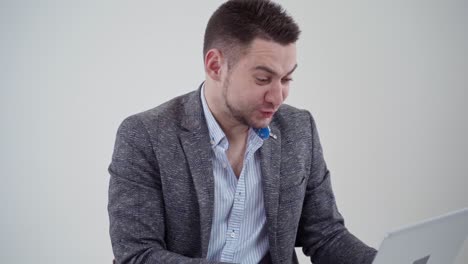 bearded man looking into laptop. handsome businessman in costume becomes very sad when finds bad information in his gadget. slow motion.