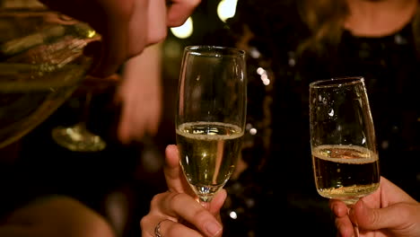 Close-up of hand pouring champagne glasses to toast at a New Year&#039;s Eve party