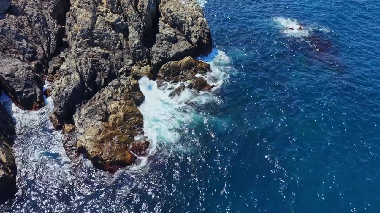 Onde si infrangono contro le rocce vicino alla riva in una giornata di sole sull'oceano