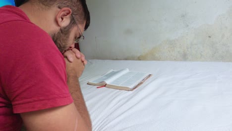 simple man praying in his room with the bible