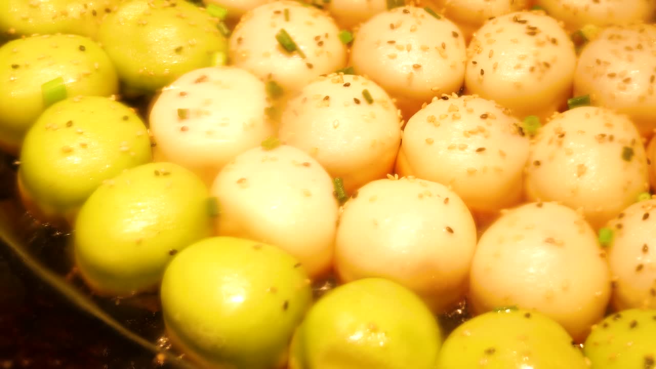 Japonya, Asya'daki bir sokak yemeği pazarında, özel kalıplanmış bir tavada mükemmel şekilde pişirilmekte olan yuvarlak takoyaki ahtapot toplarının ayrıntılı, yakın çekim görüntüsü
