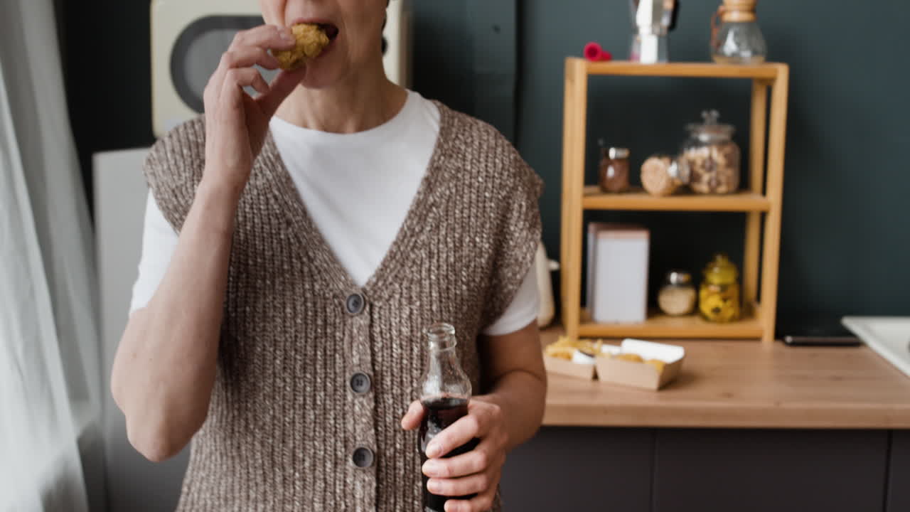 A person enjoying fast food and a beverage in a kitchen