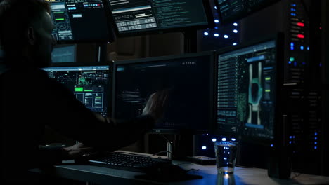 person working on multiple computer monitors in a dark control room