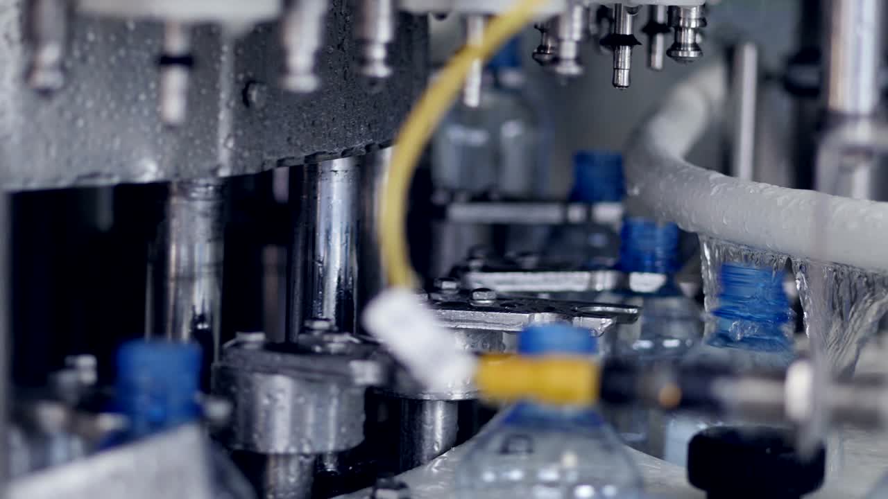 Closeup view of water bottles entering a filling machine.