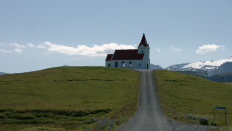 Ingjaldsholskirkja-church-on-hill,-snowy-glacier-in-background-on-sunny-day