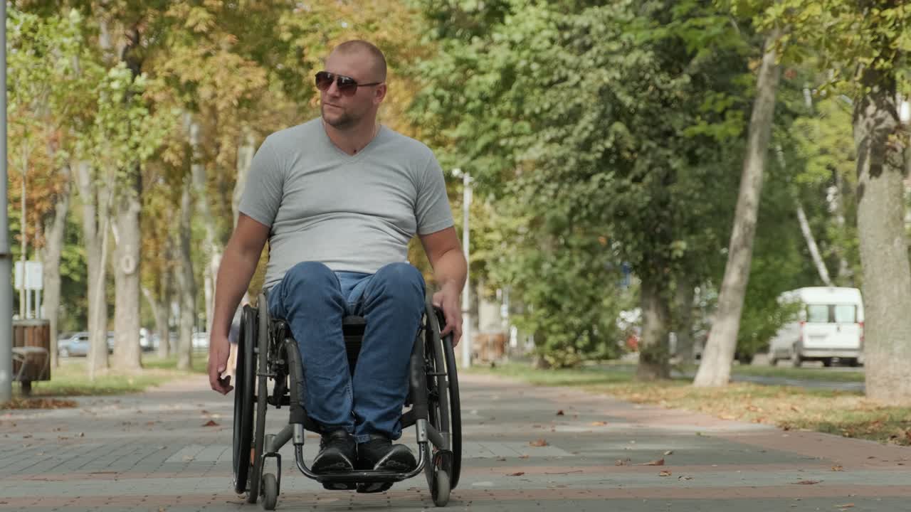 Man with disabilities in wheelchair walk at the park alley