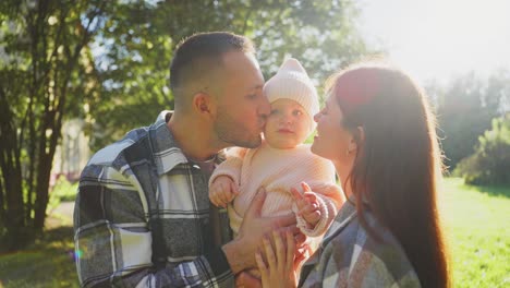 happy family kissing baby in park