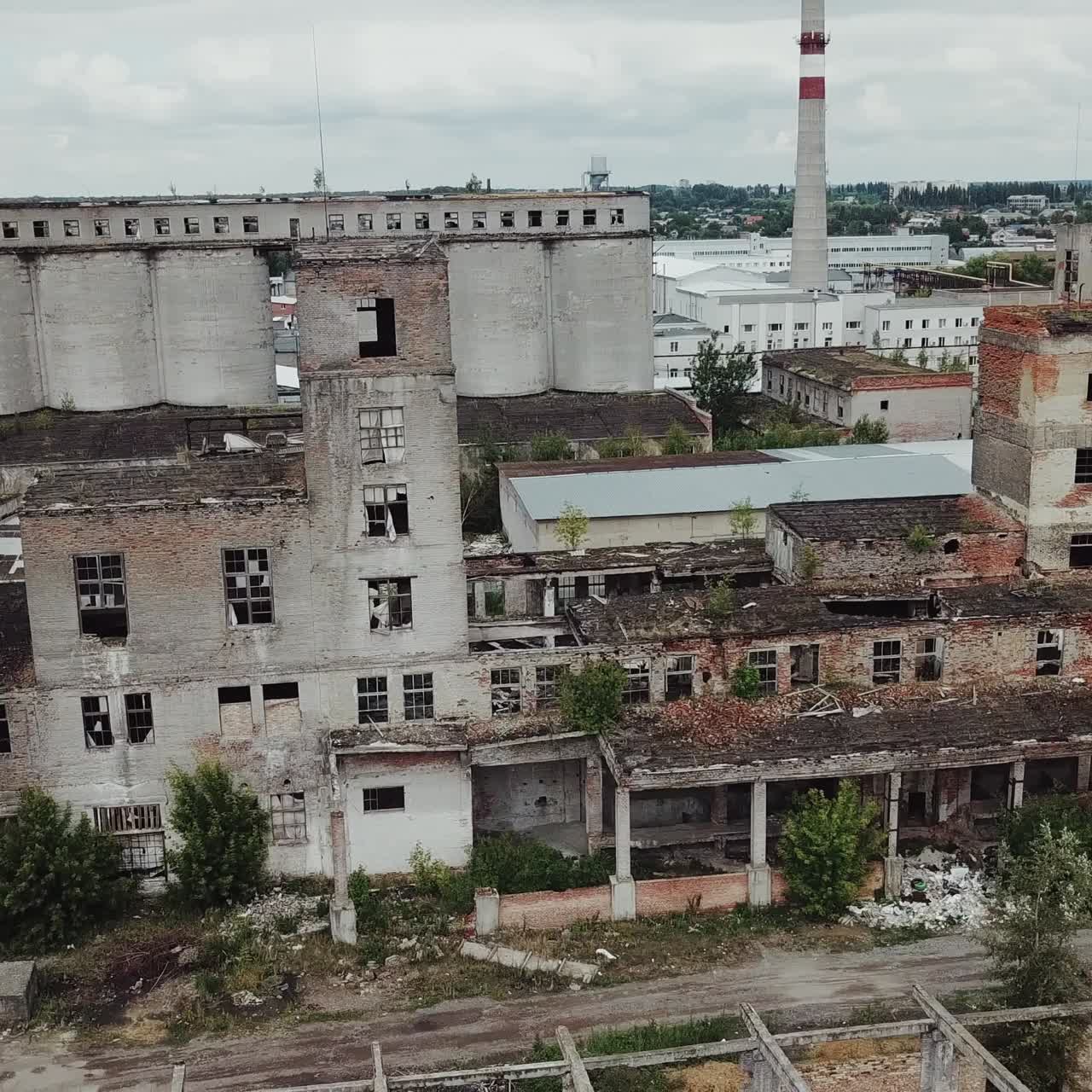 Ruins of an old factory. Abandoned building was covered with grass and trees. Holes and cracked in the walls and ceiling. Aerial view