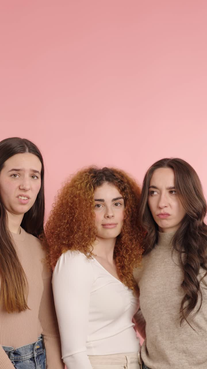 Tres mujeres mostrando expresiones juguetonas sobre fondo rosa