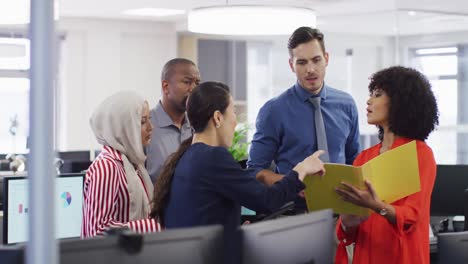 Group-of-diverse-business-people-holding-documents-and-talking-in-office,-slow-motion