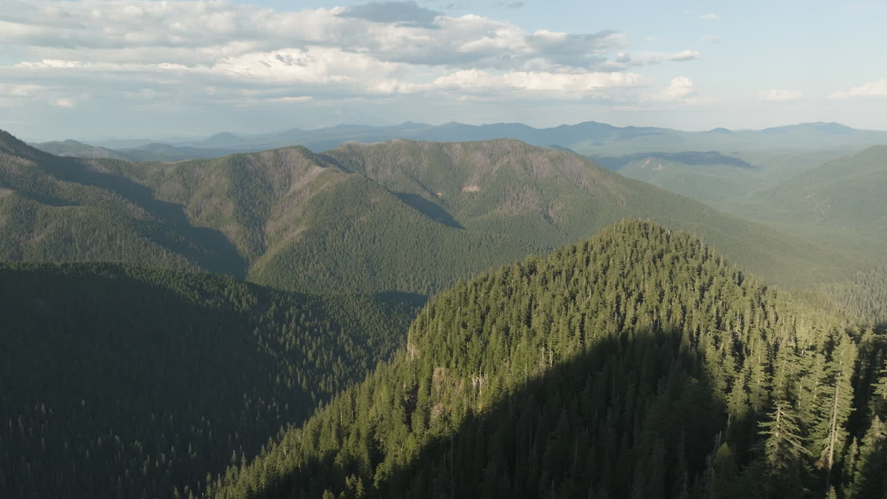 Forested peaks in Gifford Pinchot National Forest, Washington State, establishing aerial view, long afternoon shadows.