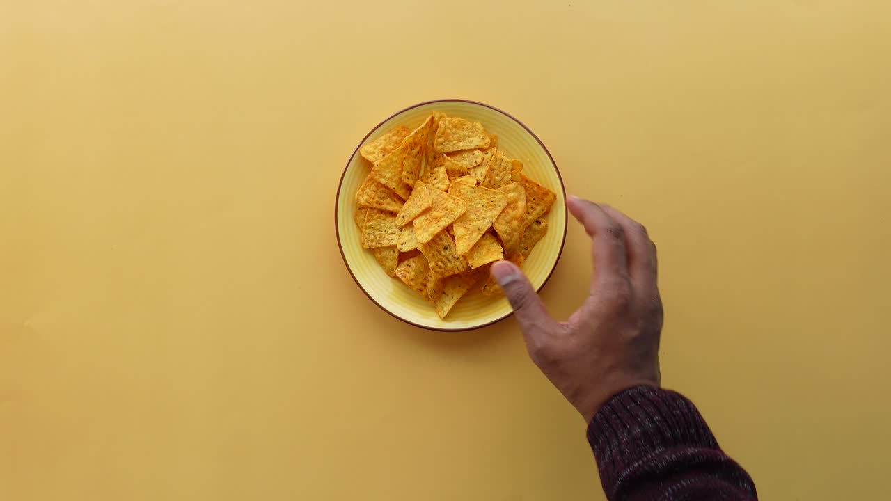 Mano che si allunga verso un piatto di tortilla chips