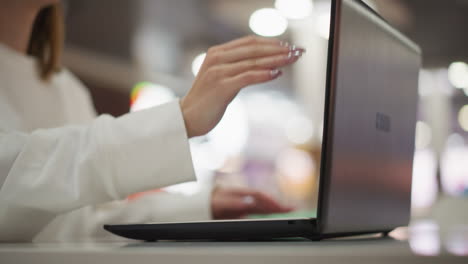 primer plano de manos escribiendo en una computadora portátil en un entorno interior moderno cierra la computadora portatil, con un vibrante efecto de luz bokeh borroso parpadeando en el fondo