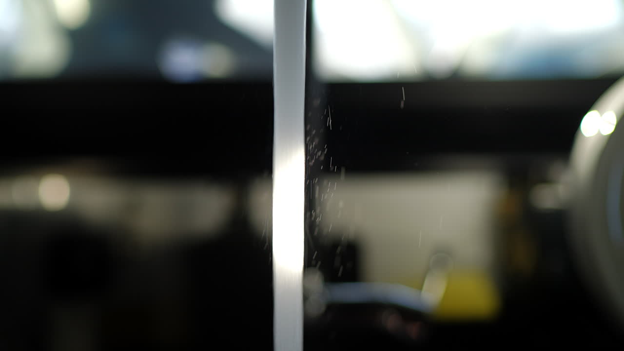 Sunlight illuminating clear, transparent water streaming from gleaming chrome faucet spout, cascading with purity against softly blurred kitchen interior background