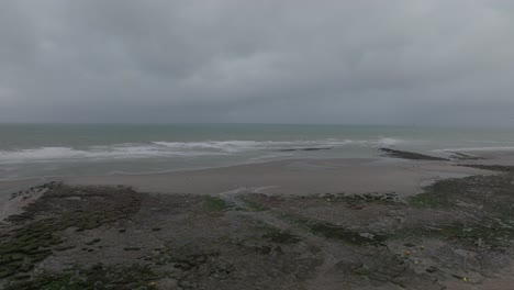 drone flying over a fort towards the sea at low tide, at the french village ambleteuse