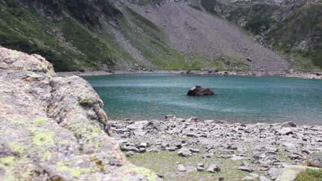 blue calm lake with a big rock in front of the view