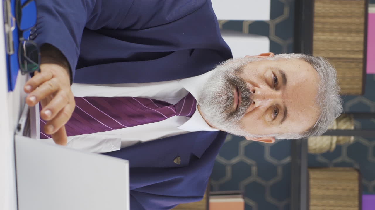 Lodret video af ældre forretningsmand, der ryster på hovedet afvisende mod kameraet