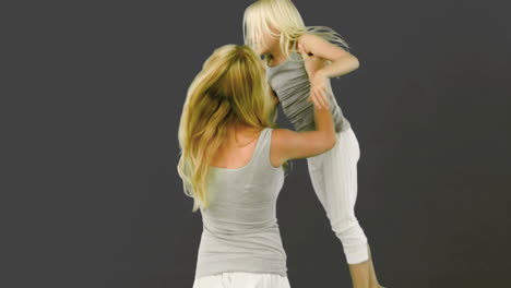 mother lifting and spinning her daughter on grey background