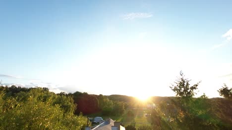 aerial ascending over trees to golden yellow sunset on horizon in orlowo