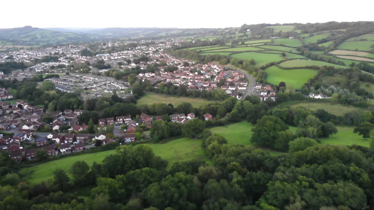 Aerial backwards shot over trees with Honiton and Devon Countryside in the background