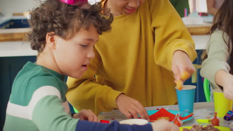 Children-Eating-Snack-Food-At-Party-To-Celebrate-Birthday-At-Home