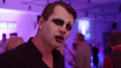 man with face paint and party in background, closeup portrait