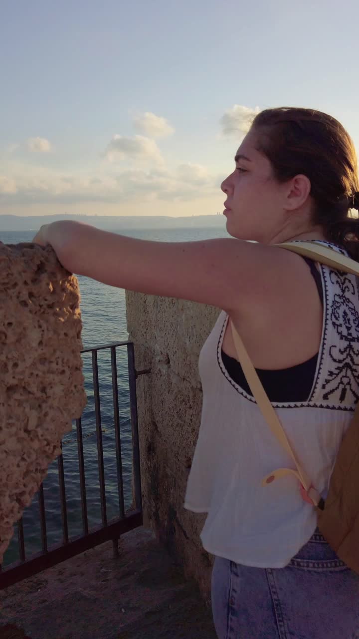 Young woman tourist waving from ancient city walls of Acre, Israel