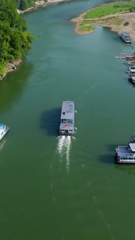 vertical drone shot following a lijiang river cruise ferry in yangshou, china