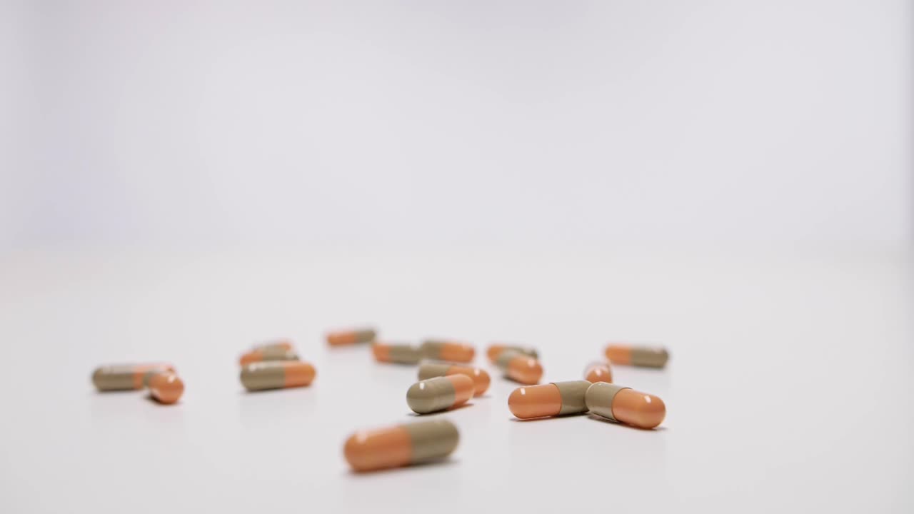cápsulas de medicina cayendo sobre fondo blanco en cámara lenta