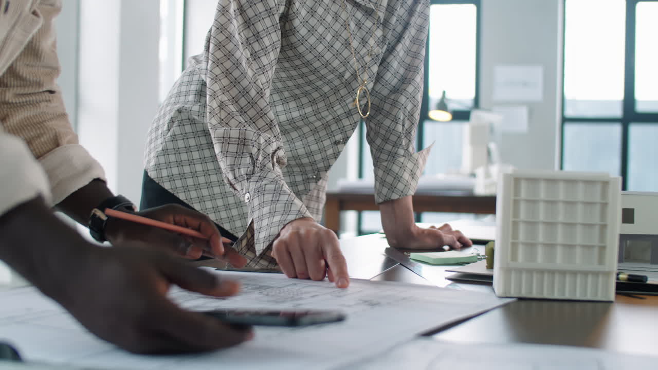 다민족 남녀 동료 들 이 건축 계획 을 논의 하고 있다