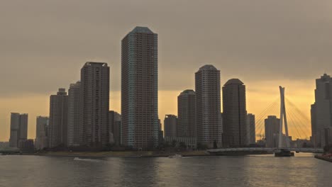 a scenic view of the sumida river in tokyo at sunset, featuring the river city 21 skyline and a bridge in the distance.