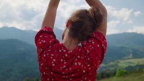 woman relaxing raising hands to cloudy sky closeup. back view girl enjoying rest