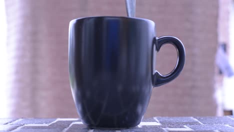 stirring a drink in a black mug