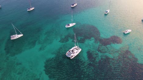 Drifting-yachts-in-the-bay-near-the-coastal-city-of-Croatia-against-the-backdrop-of-blue-skies-and-blue-transparent-water