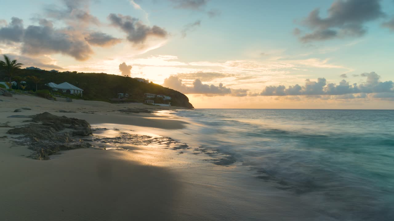 tomada de timelapse de olas continuas en la costa de la playa de baie rouge en saint martin con nubes cumulus en el cielo