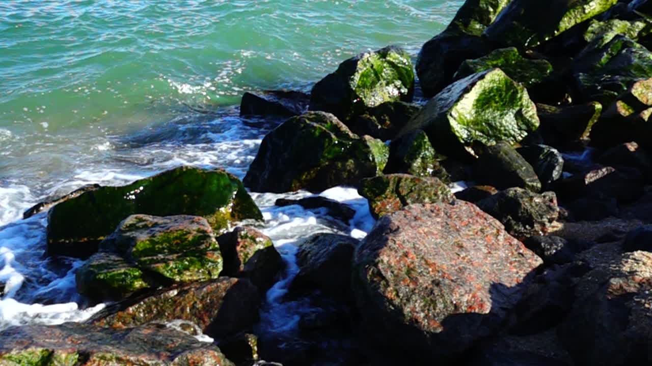 Onde del mare si infrangono contro le pietre. Riprese sulla costa. Slow motion